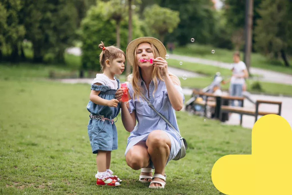 Maman et sa petite fille s'amusant à faire des bulles dans un parc.